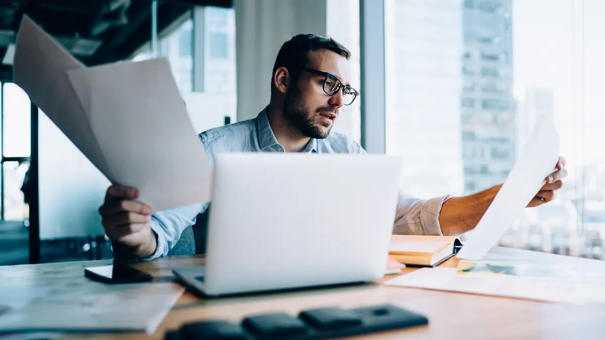 Contractor reviewing project documents trying to figure out how to file a mechanics lien at a desk in a high-rise office