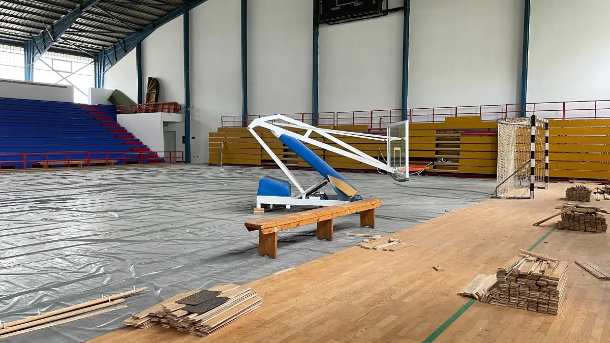 Unfinished gymnasium construction project with flooring materials left idle mid-installation